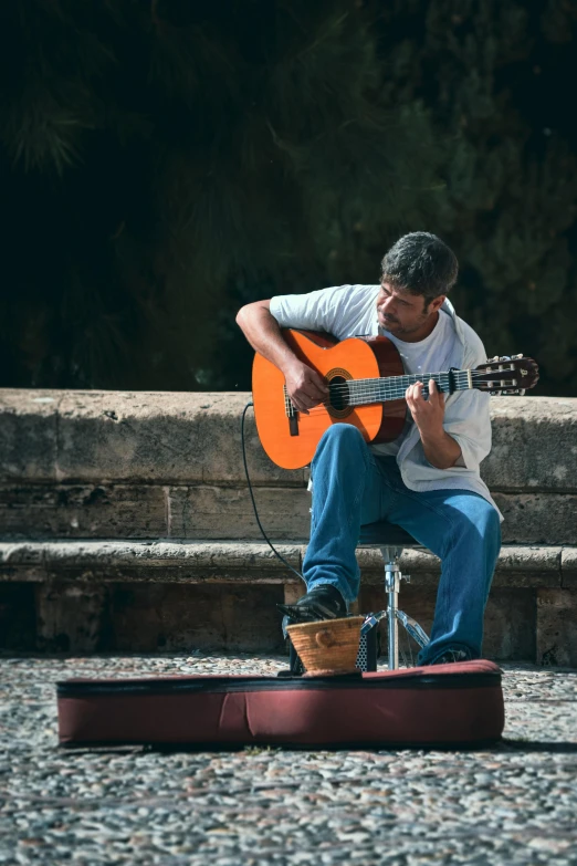 a man sitting on the ground playing a guitar