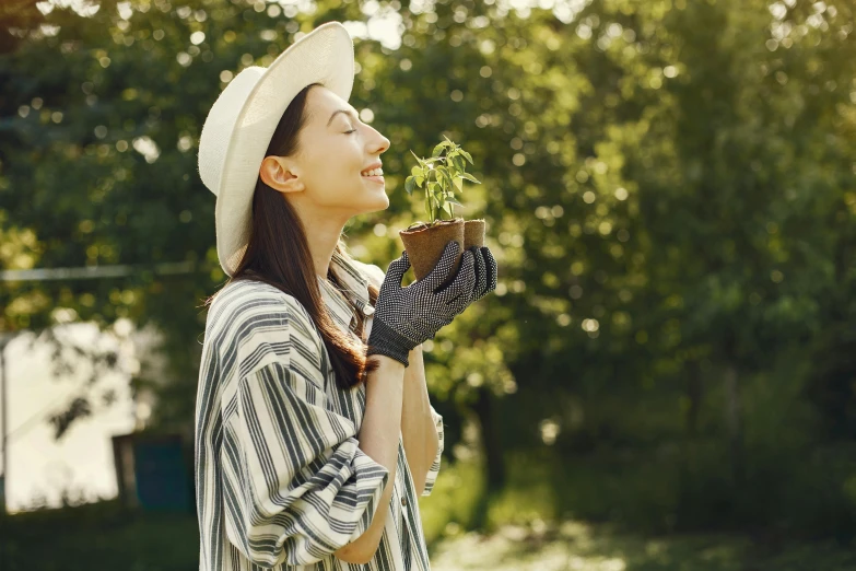 a woman in a hat and scarf holding a plant