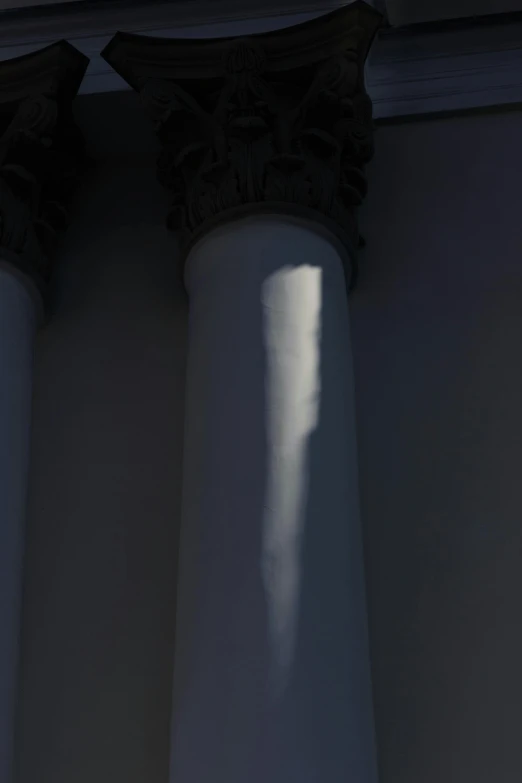 a light shines down from the top of three white pillars