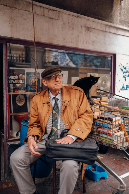 a man sitting down with a cat behind him