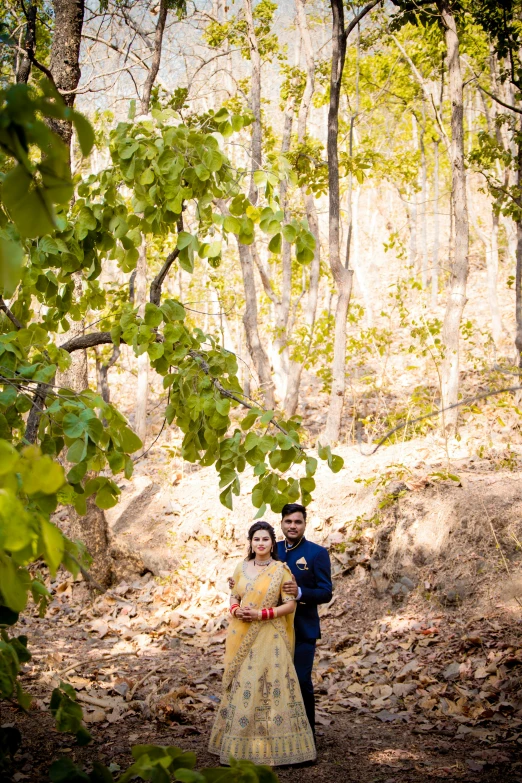 a newly married couple standing under the trees in a wooded area