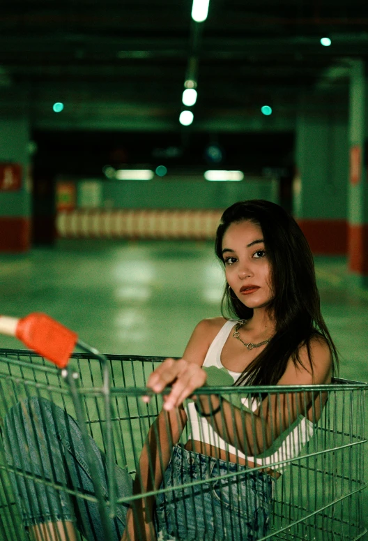 a woman with a red tennis racquet in her hand sits inside a shopping cart in an empty garage