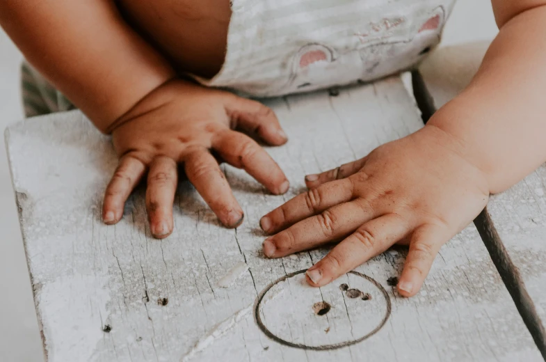 a child holding their hands over soing on the wooden table