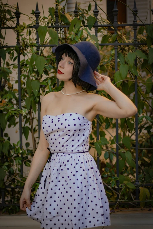 woman wearing a white dress and black hat with blue dots