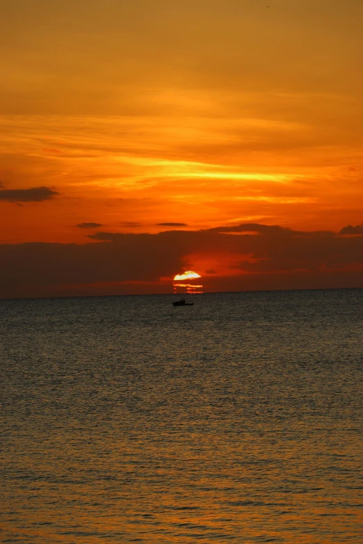 a ship is silhouetted as the sun sets in the sky