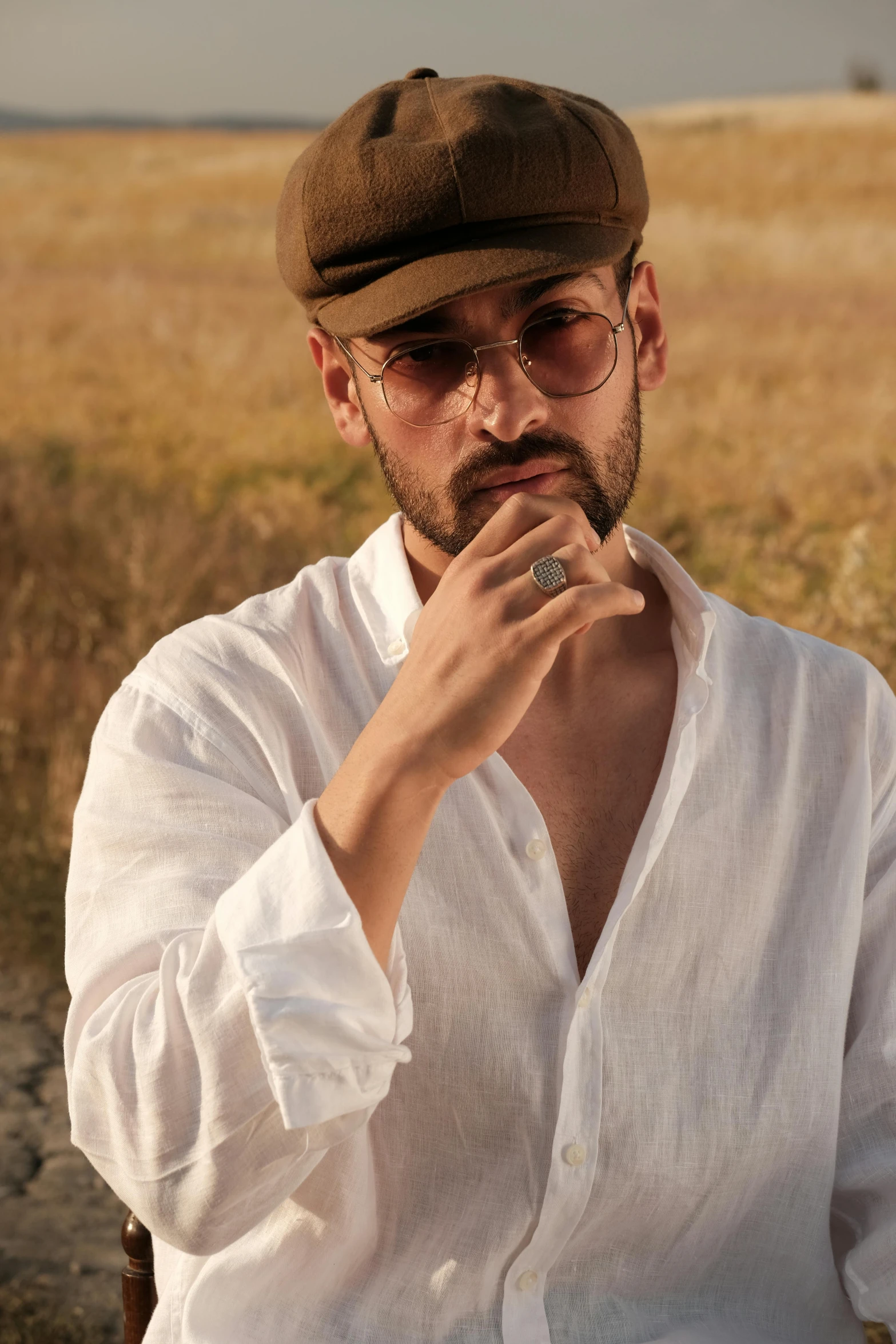 a man wearing glasses and a hat looks off to his right