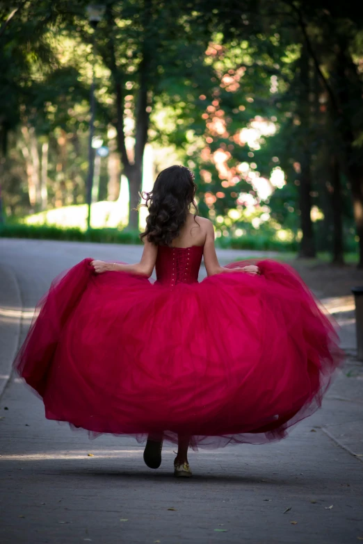 girl in red dress walking down sidewalk through park