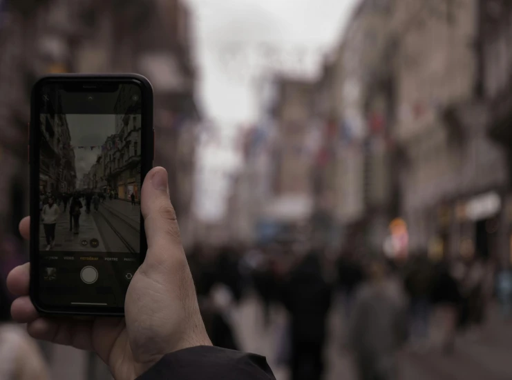 a person is holding up their phone to take a picture of people walking