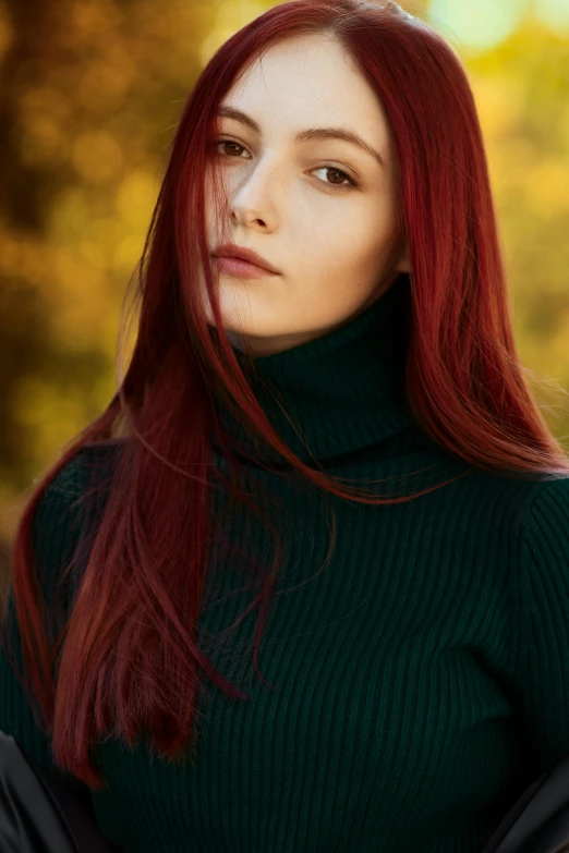 woman in green sweater sitting in forest with trees