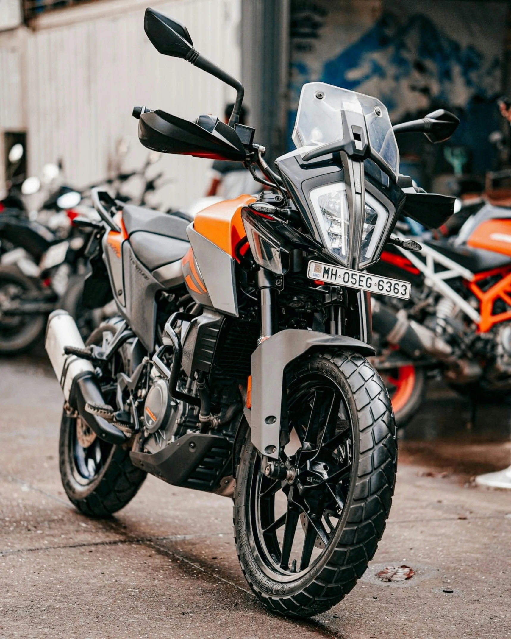 motorcycles parked on the street and one has an orange color