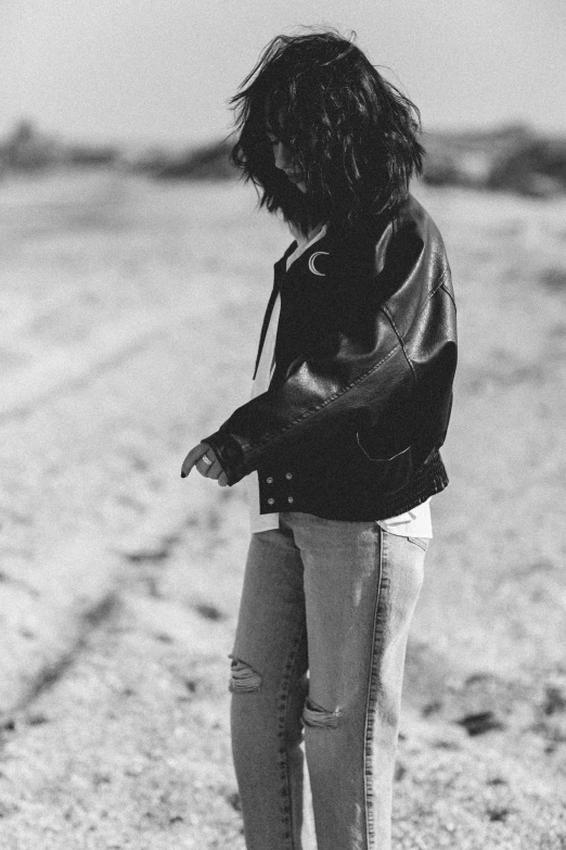 a woman standing on the sand with her arms in the air