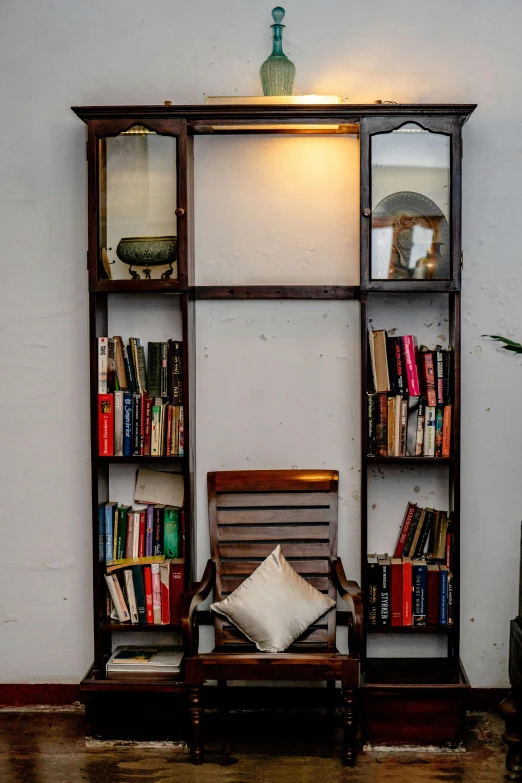 an old style chair and bookcase in front of a wall filled with books