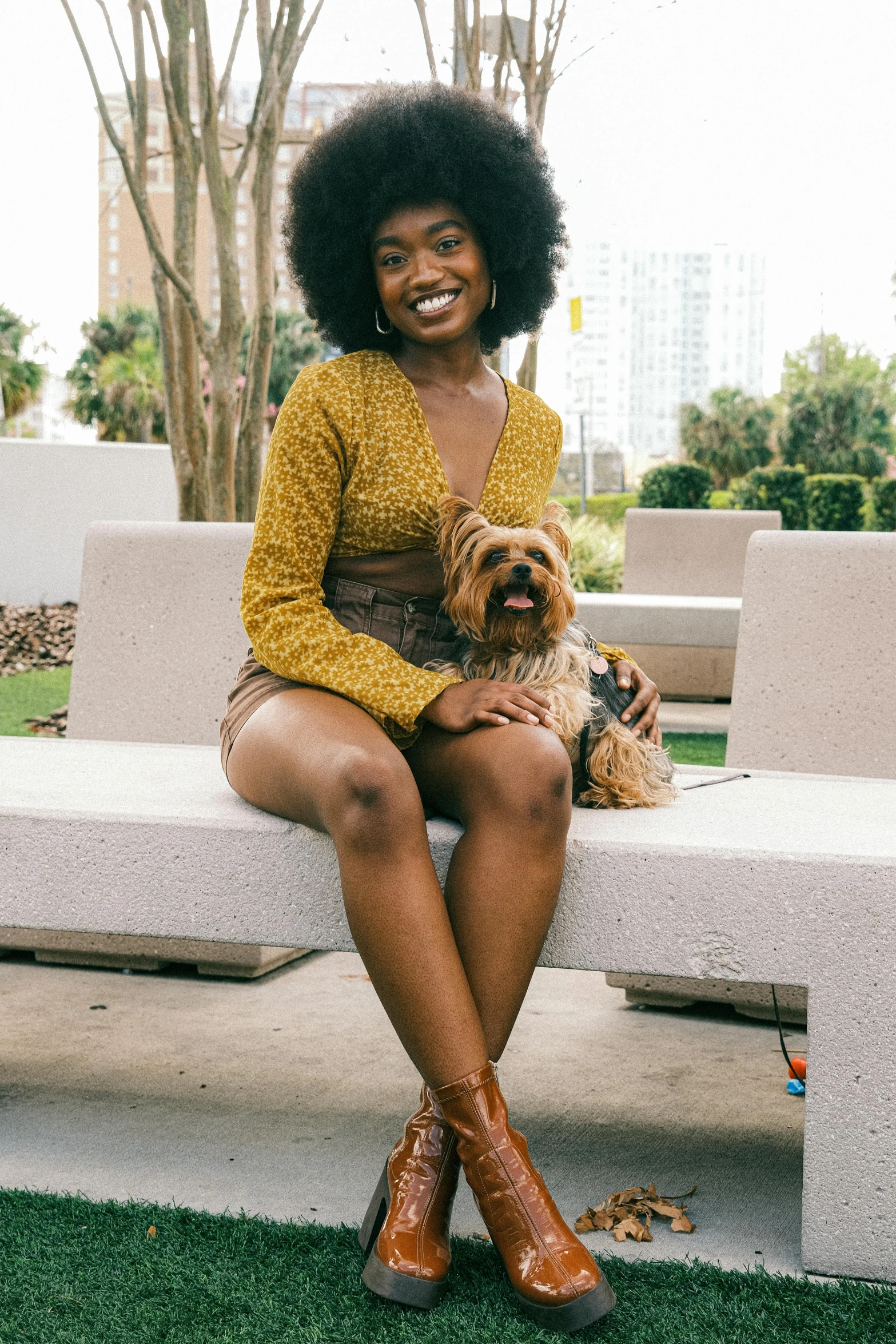 a black woman sits on a bench and holds her dog