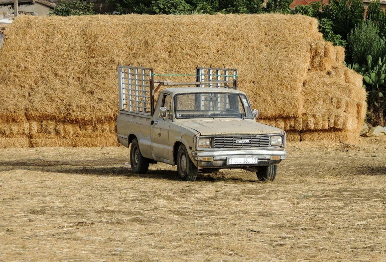 a truck is sitting on the dirt and hay