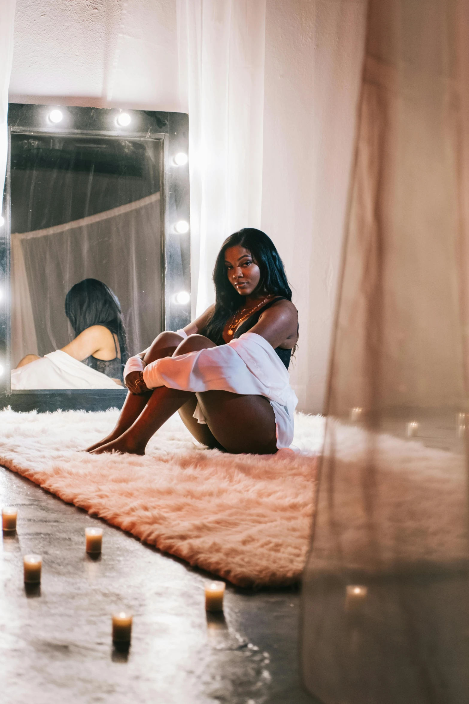 young woman sitting in front of large mirror next to candles