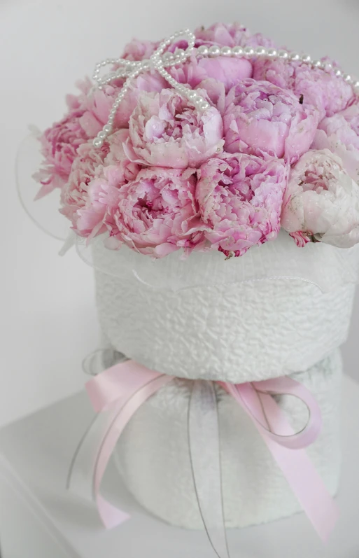 a white hat holds pink flowers in it