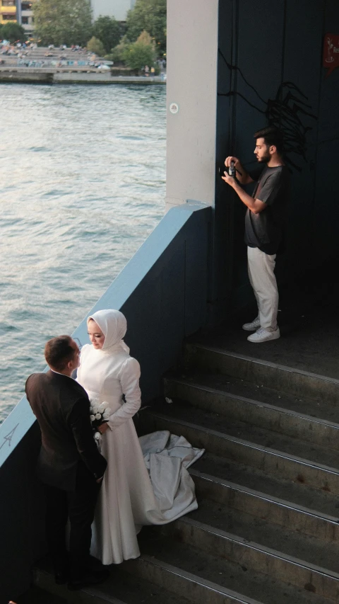 a bride and groom taking pictures at the steps by the water