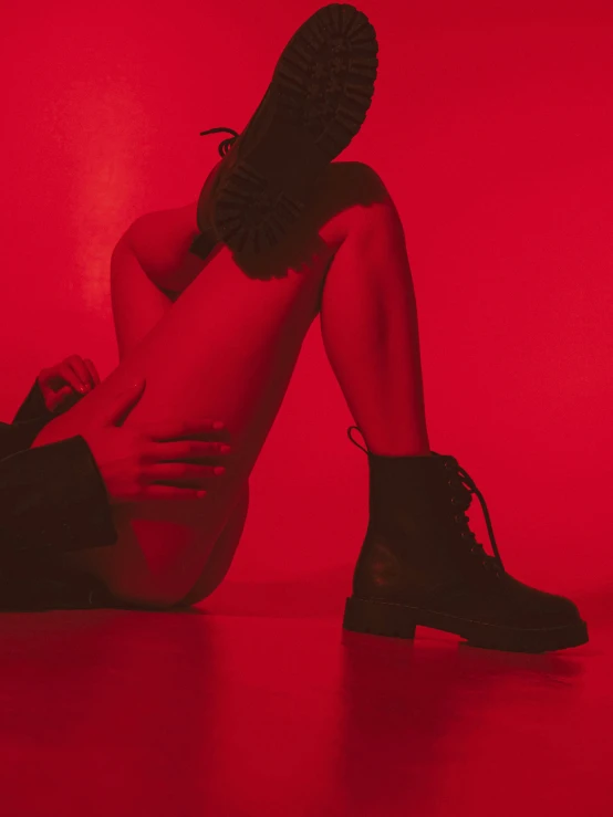 a girl in black boots sits on the floor