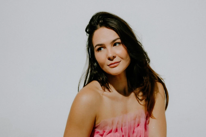 a woman wearing a pink strapless dress poses for a picture