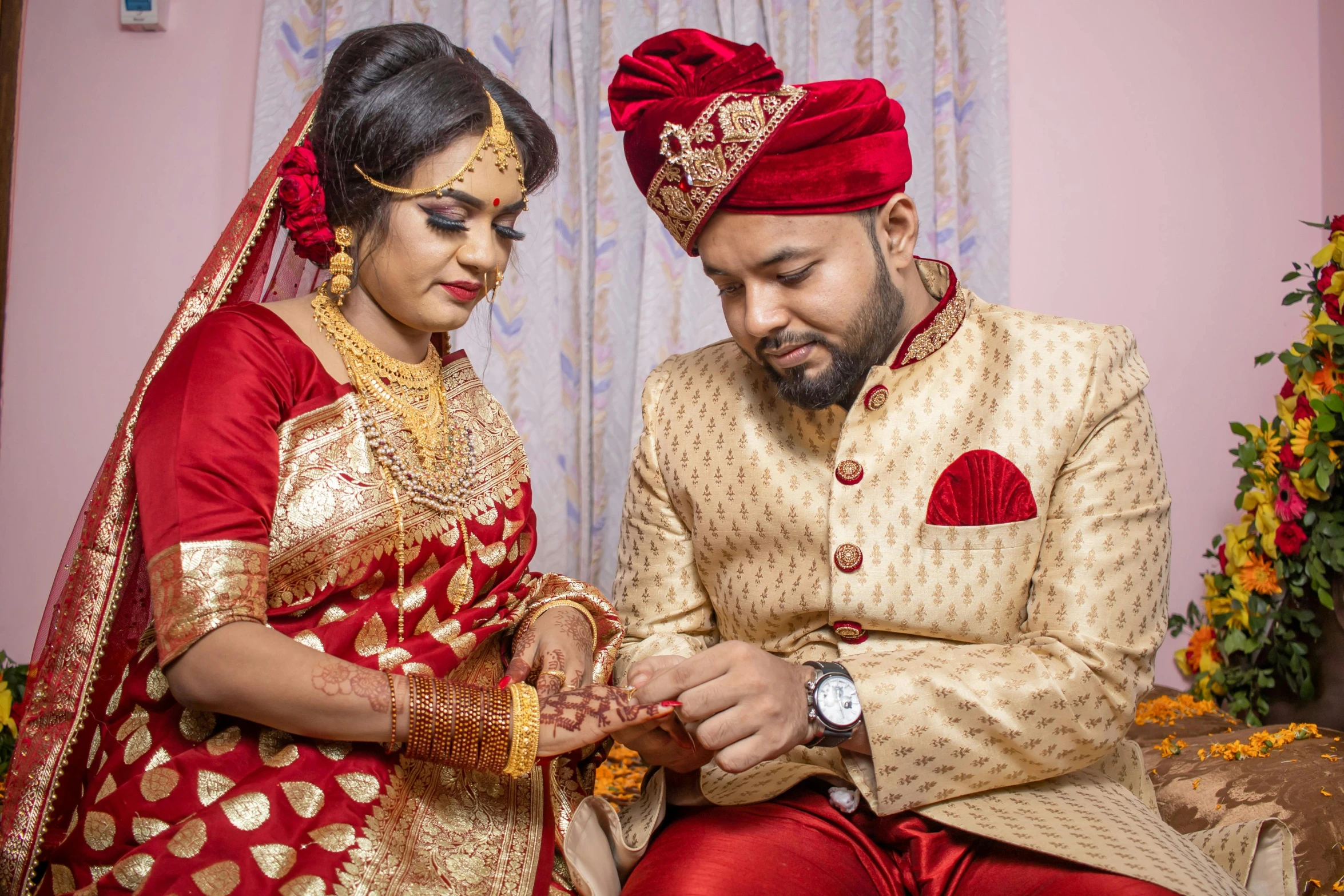 a man and woman wearing indian attire look down at the wedding ring