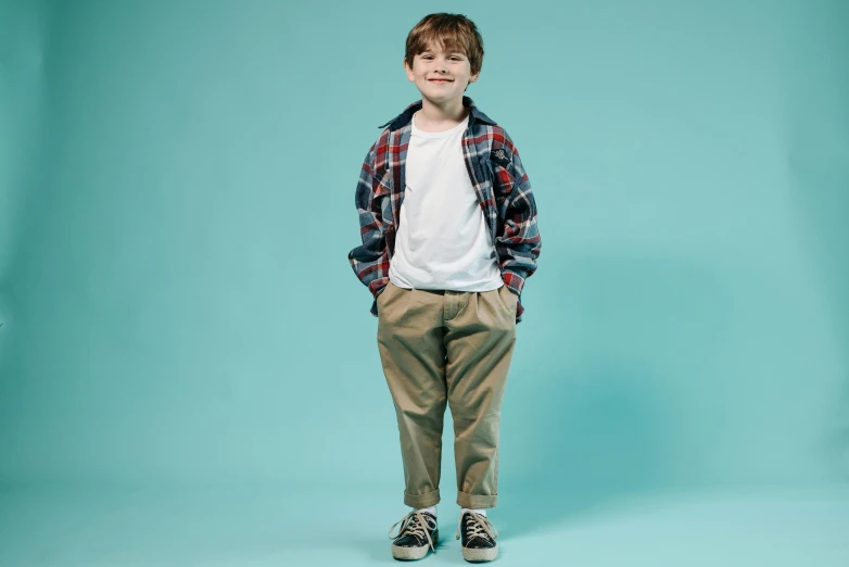 boy stands on aqua background and smiles at the camera