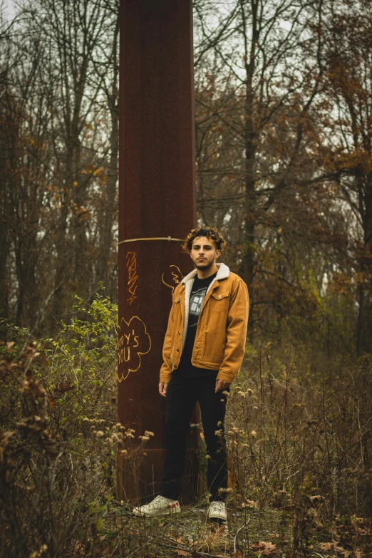 a young man standing beside a tall red pole