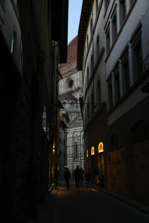 some people are walking down an old narrow street