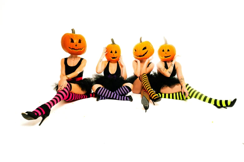 three girls wearing funny pumpkin faces sitting down