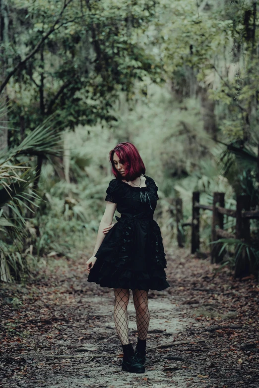 a  in black dress walking down a dirt road