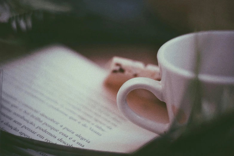 the coffee mug on the open book is sitting on the table