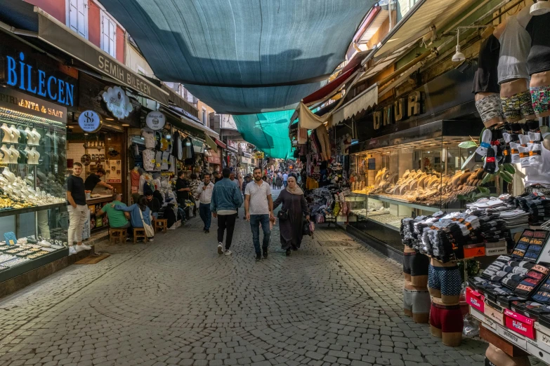 people walk through an open market filled with souvenir