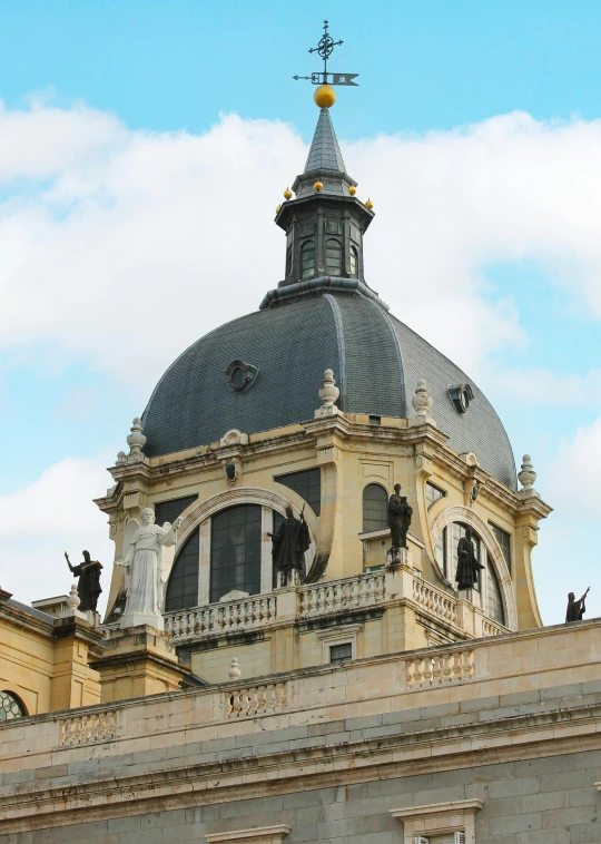 the top of a dome on a building that has statues around it