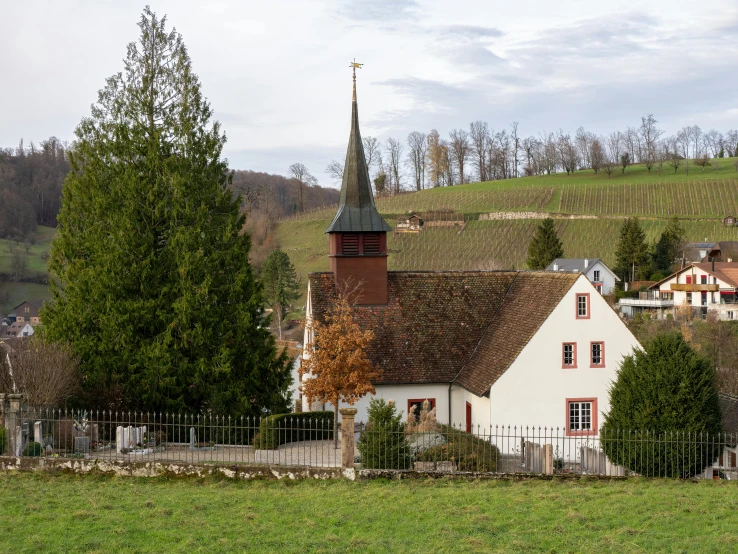 a white church with a brown roof and green grass and trees