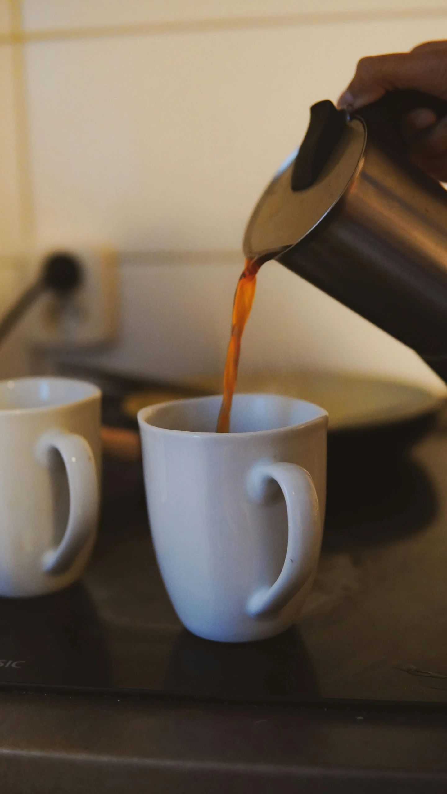 coffee being poured into two white mugs