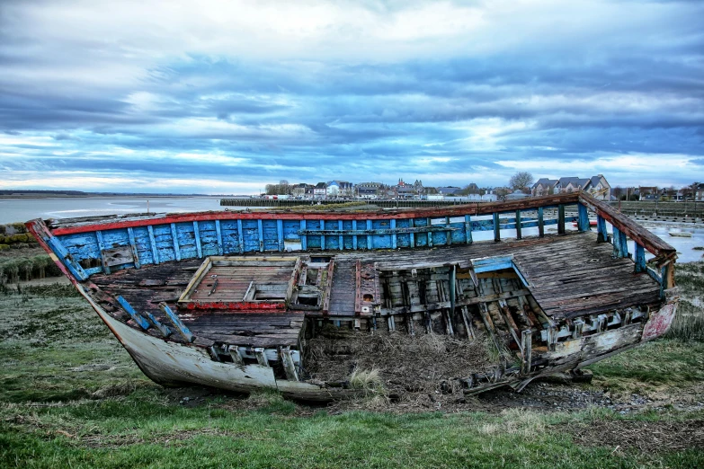 the very old boat sits in the grass by the water