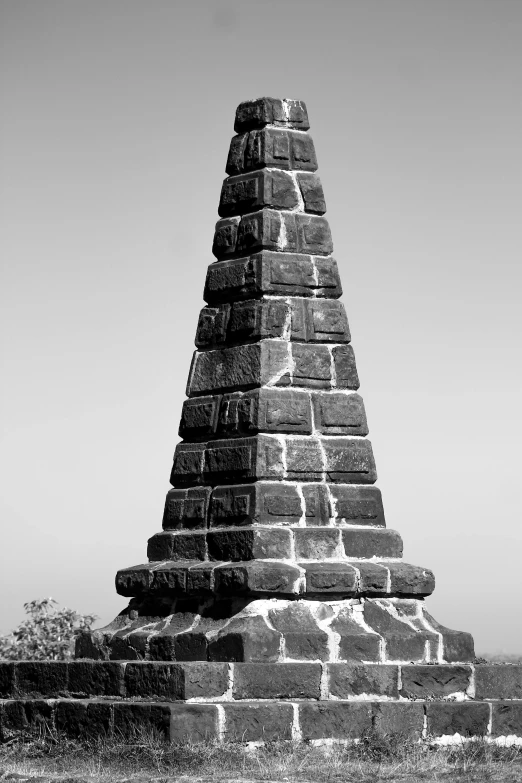 a big black pyramid made of bricks sitting next to a grassy field