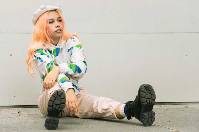 a girl with pink hair and long sleeves sitting on concrete