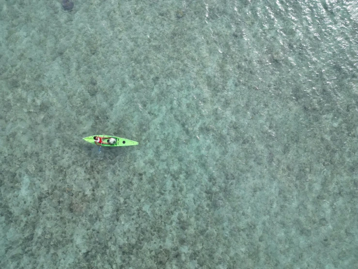 a man on a green boat in blue water