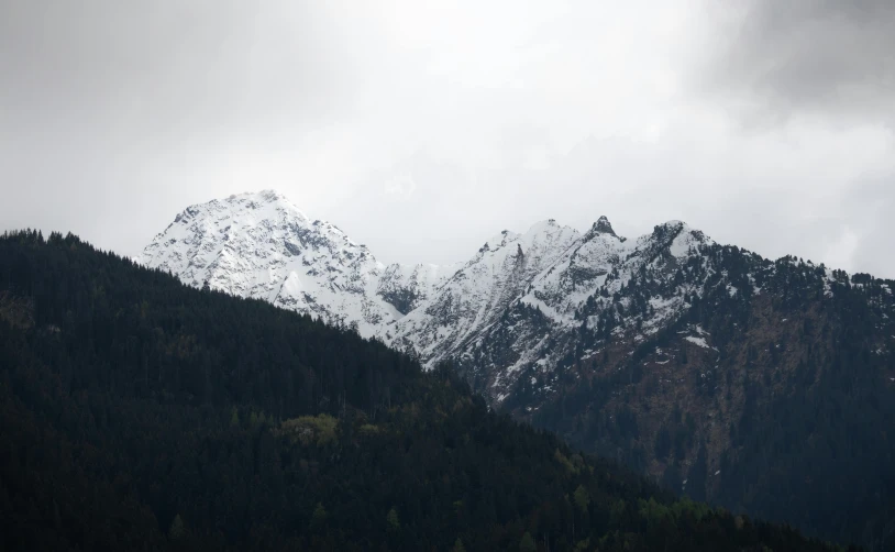 a mountain range in the mountains with evergreens and dark clouds