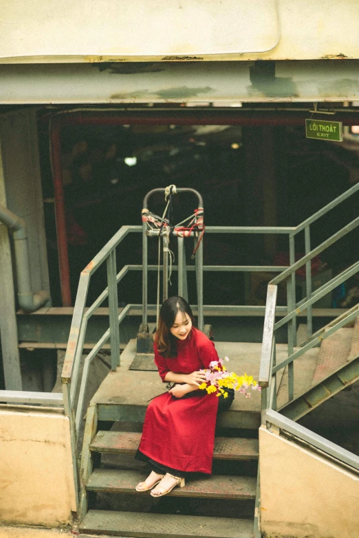 the woman sits on a stair case outside of a basketball court