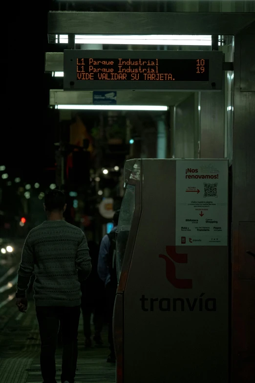 people are walking along the sidewalk at night