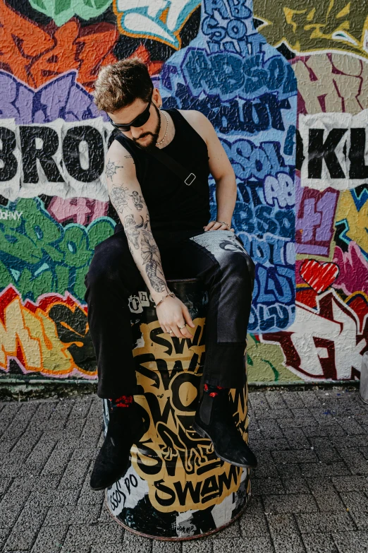 a young man sitting on top of a graffiti covered skateboard