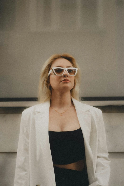 a woman in a black dress and white jacket with sunglasses on