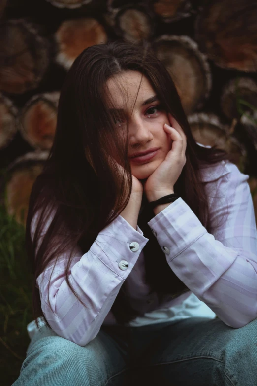 a woman in a white shirt sitting next to logs