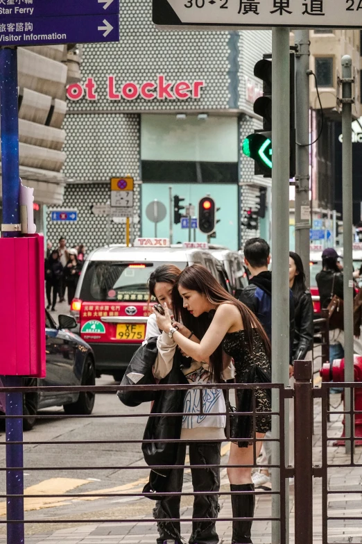 two women on the street are using their cell phone