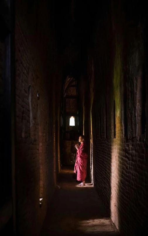 a person standing in a hallway next to a brick wall