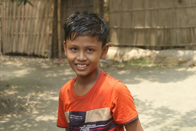 a boy standing in front of a fence holding a cell phone