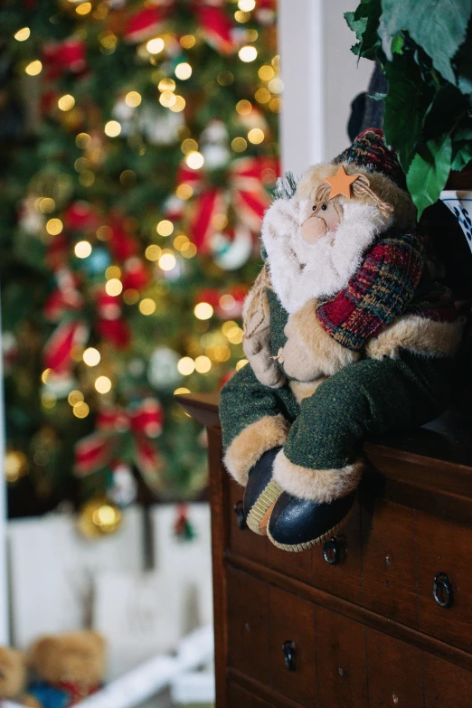 a decorative, colorful gnome sits in front of a christmas tree