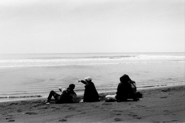 four people sitting on the beach enjoying a day out