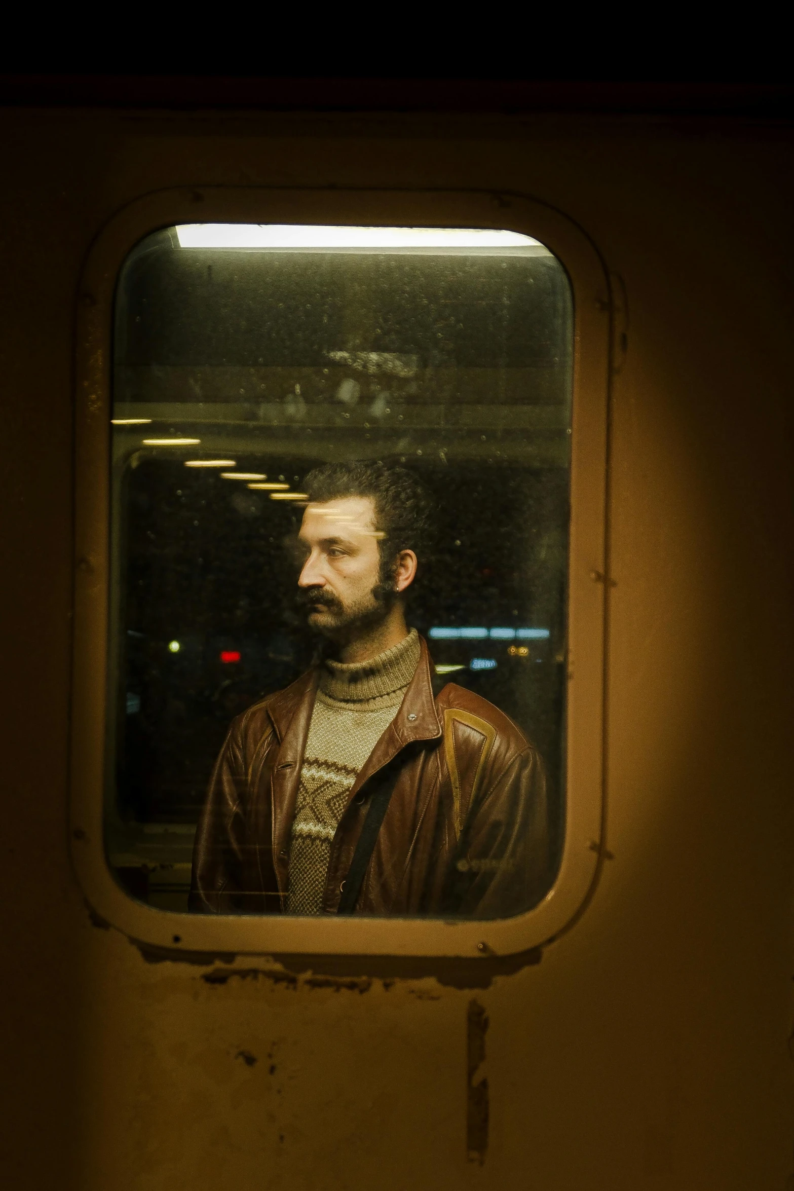 a man in leather jacket looking out the window